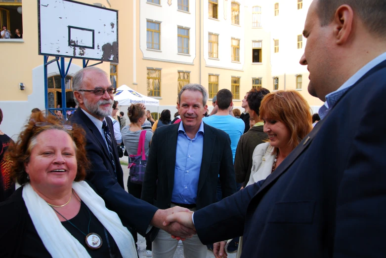 two men shaking hands at a crowded outdoor gathering