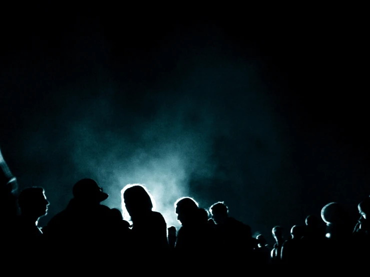 a dark crowd of people standing around each other