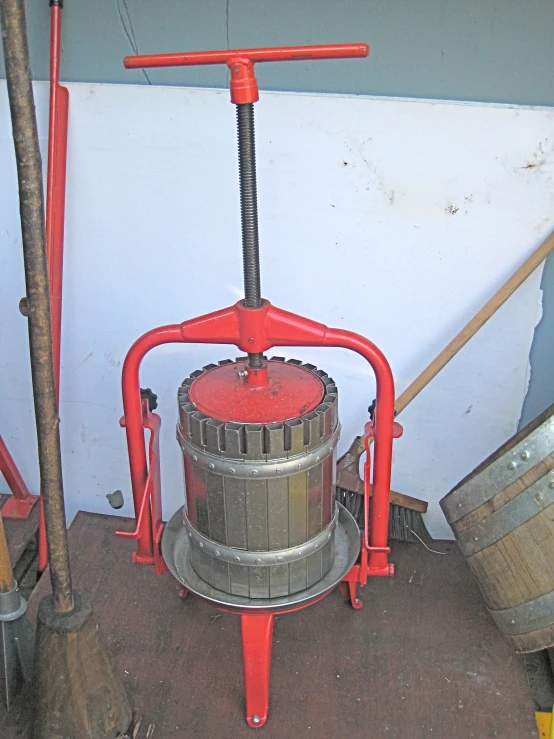 a red machine with a plunger sits next to buckets and other items