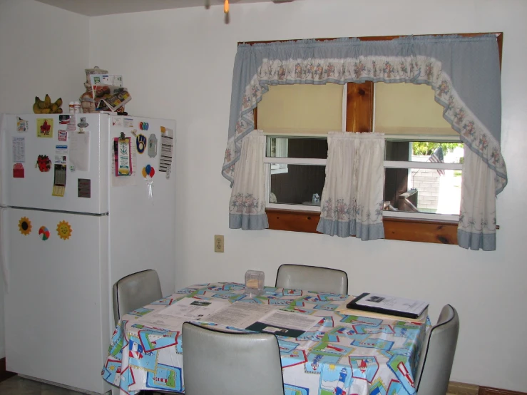 a kitchen area features a fridge and a table with chairs