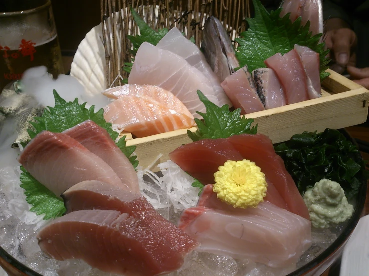 an assortment of sashimi sitting on ice in a basket
