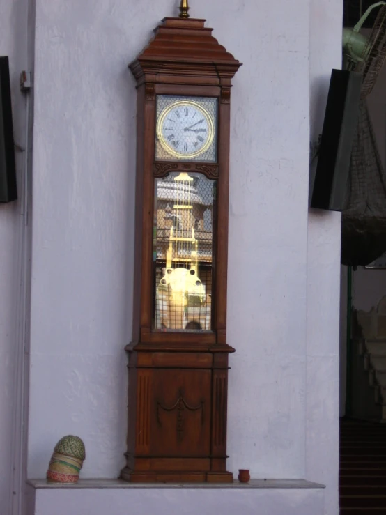 a grandfather clock sits in a corner with no glass