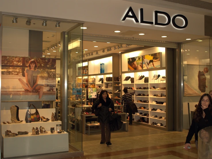 two women standing outside a store front with lots of shoes on display