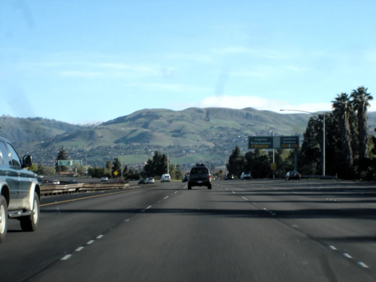 cars driving on a freeway with mountains and hills in the background