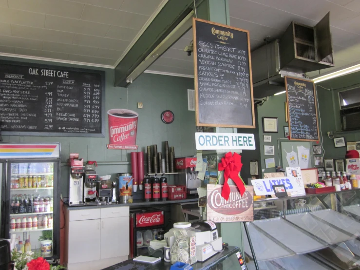 an open coffee shop with chalkboard menus, soda machine and food