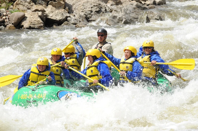 a group of men and women riding on the back of a green boat