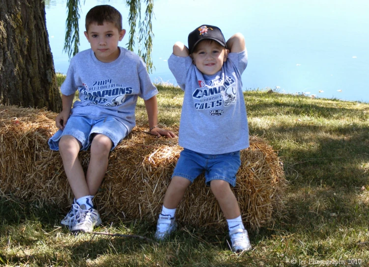 two children sitting next to each other on top of hay