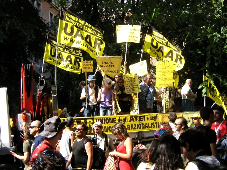 a man on stage with some people holding yellow banners