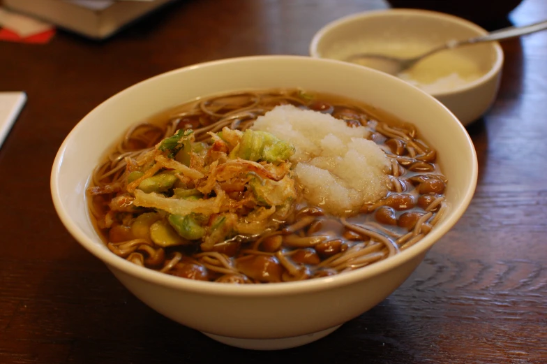 noodles, meat and vegetables are in a bowl with chopsticks on the side