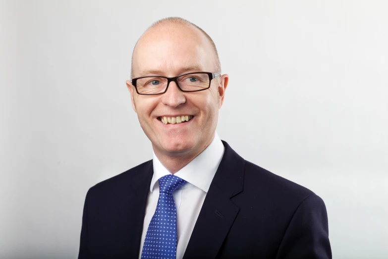 man with glasses and a suit smiling for a picture