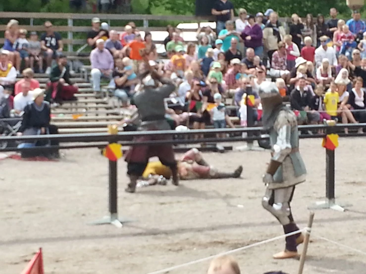 men dressed in medieval period clothes stand behind a wooden fence