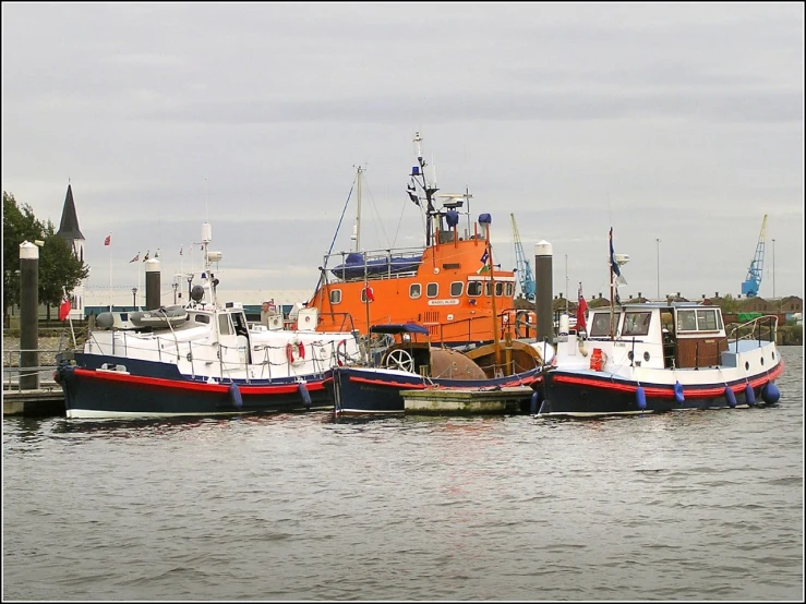 several tugboats sit parked at dock next to each other