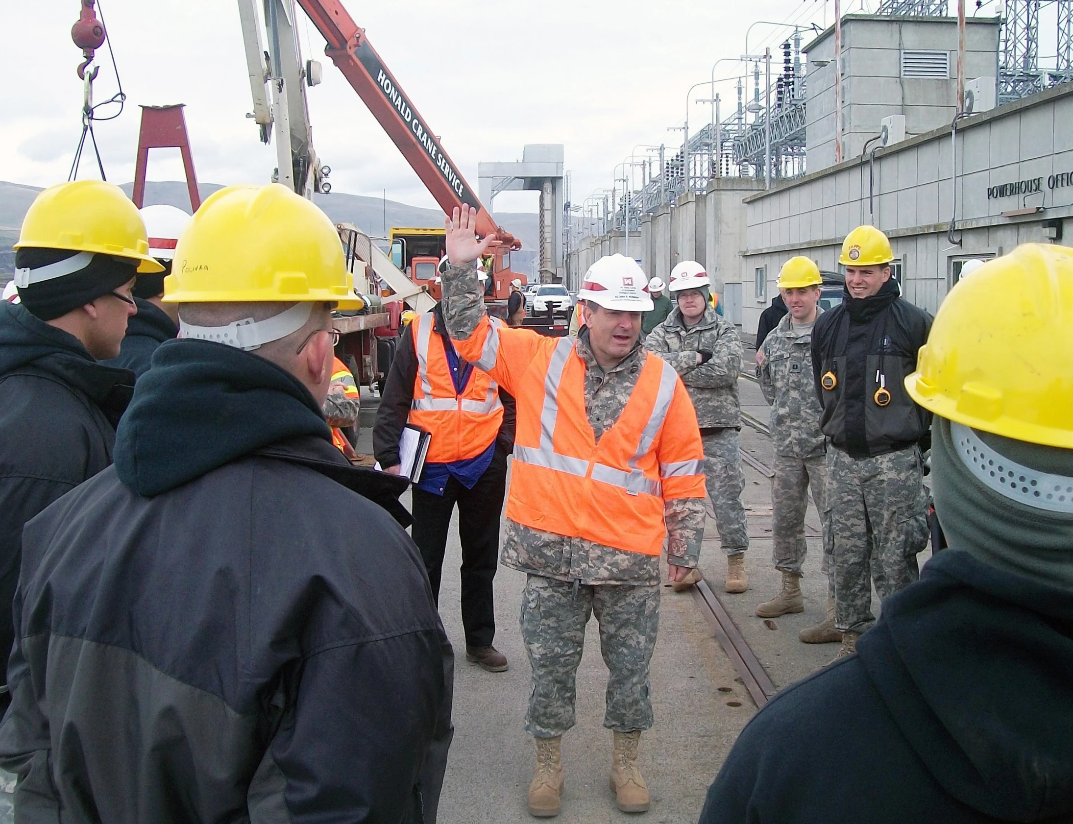 some men wearing orange helmets and yellow safety vests