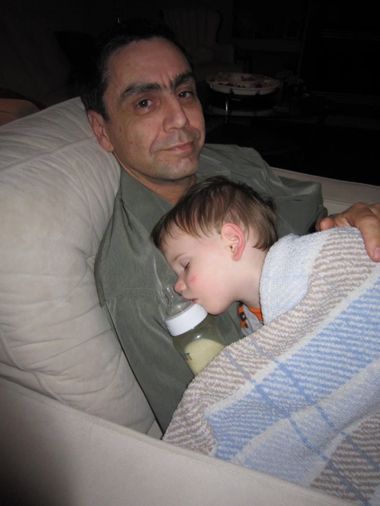a man sitting in a chair holding a child wrapped in blankets