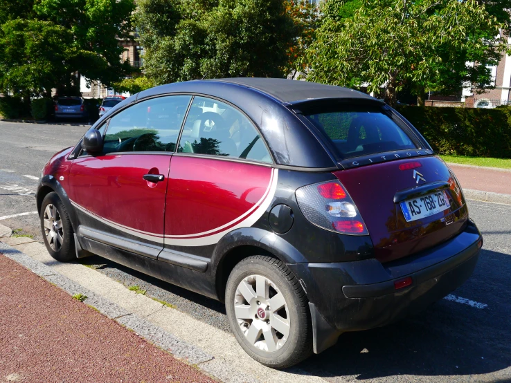 the back end of a red and black car in front of a street