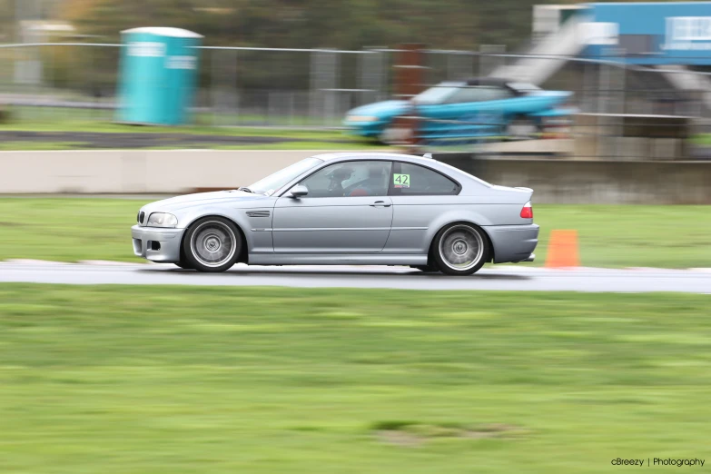 a silver car driving on a track at a race