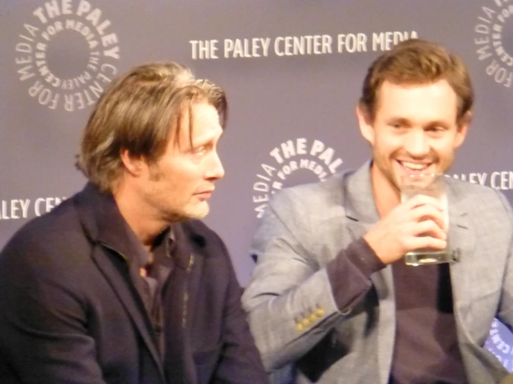 two men are talking while holding drinks together