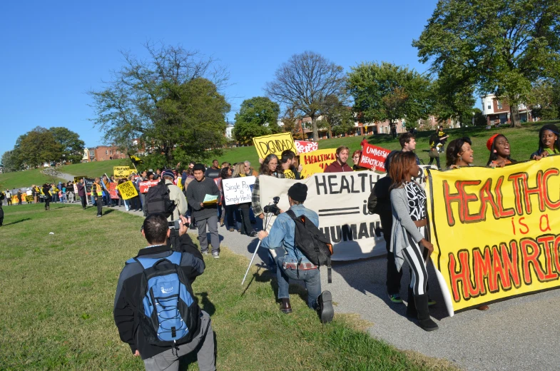 a group of people with banners standing on the side walk