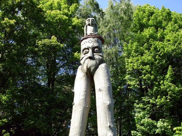large wooden sculpture in forest with a man face
