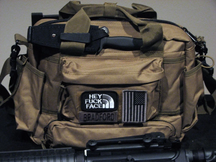 a tan bag with patches and the gun to it,
