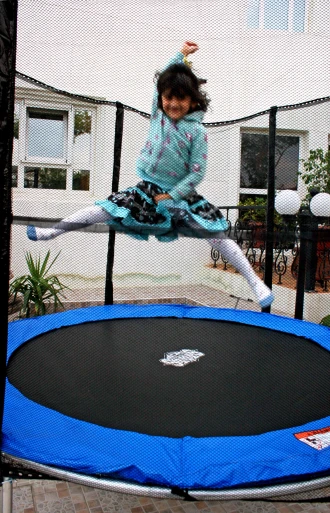 a young child jumping on a trampoline outdoors