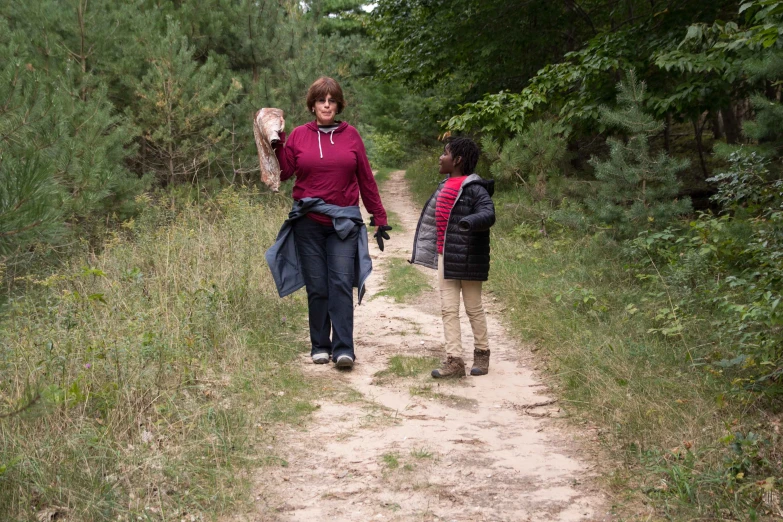 two women walking along a dirt path through a forest