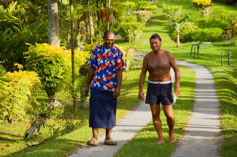 two people are walking on the path in a tropical area