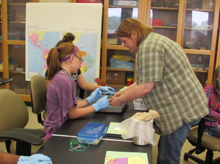 a woman is teaching students how to use gloves on her