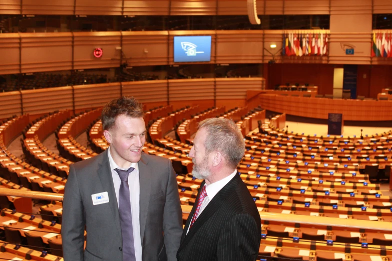 two men standing next to each other at an auditorium