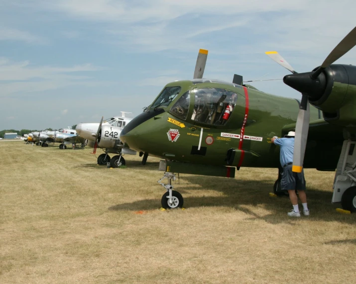 a man leaning on an old army airplane