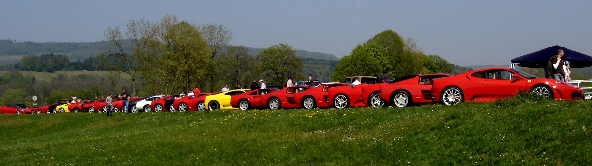 a line of cars are parked on a grassy hill