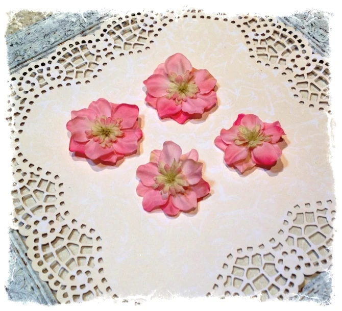 pink flowers are in the center of this white lace doily