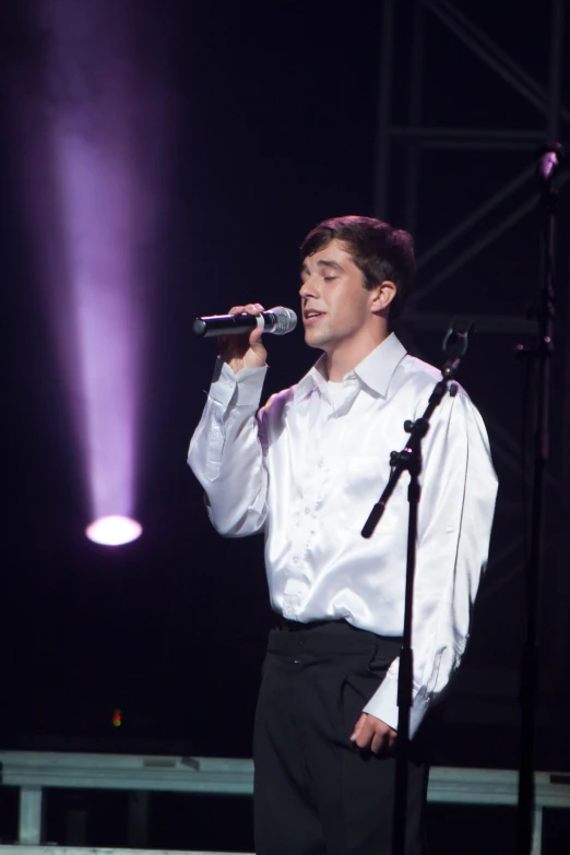 man in formal clothing singing into microphone during event