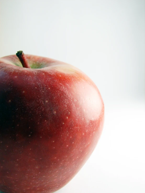 an apple sitting on a white surface with white background