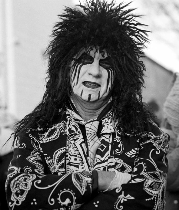 man wearing elaborate headdress, black shirt and tie