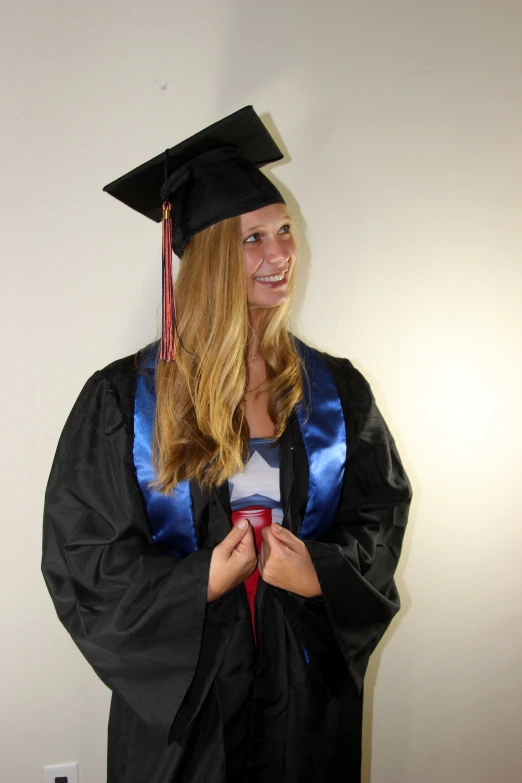 a young woman standing wearing a graduation gown and cap