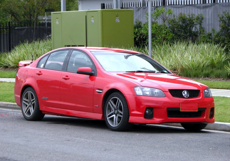 red car parked next to a black paved road