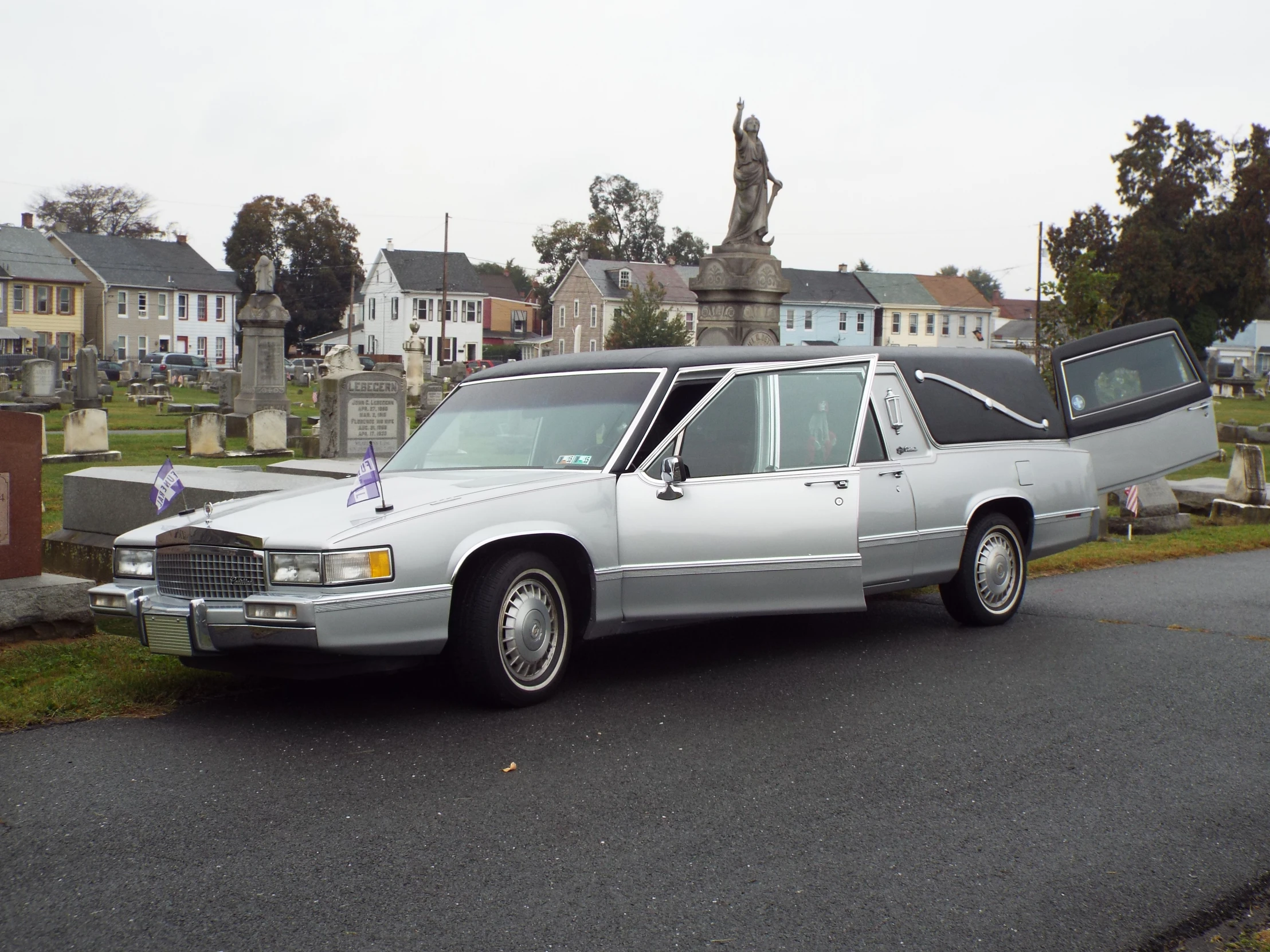 a car with a casket door in the hood on a cemetery