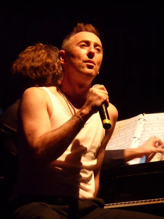 a man is singing into the microphone as the woman holds a book