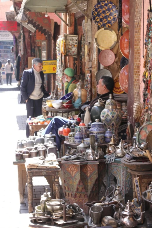 several items for sale on the sidewalk as a man walks by