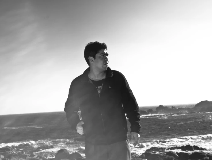 man standing on the rocks in front of a body of water