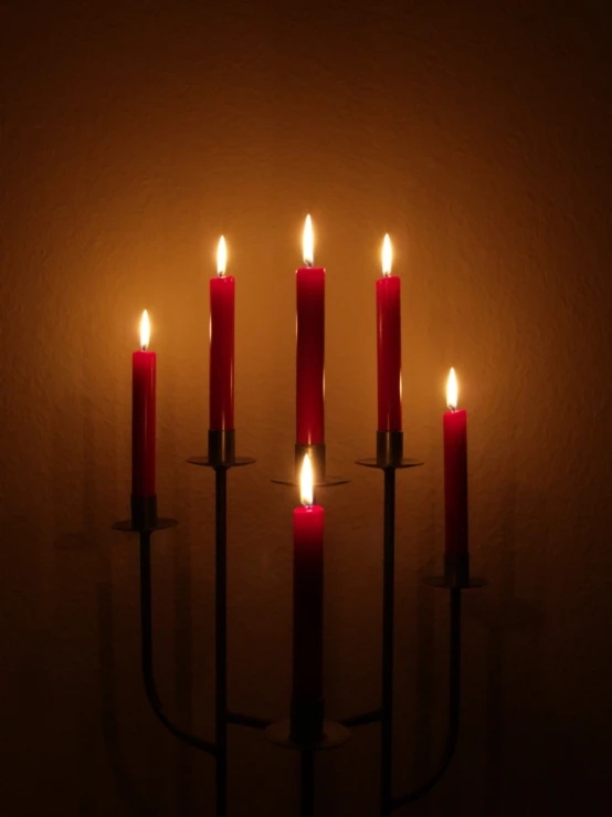 several lit red candles are sitting in a dark room