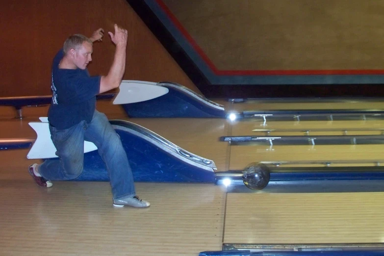 a man is kneeling down to shake the pins on a bowling alley