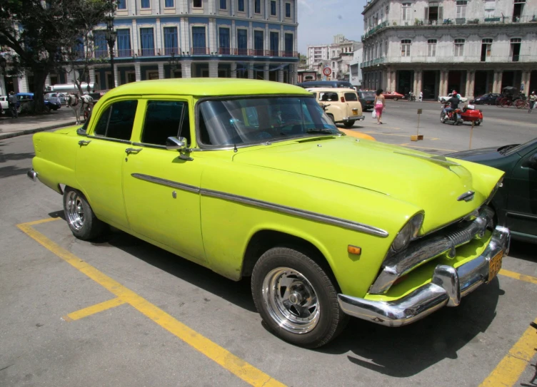 the old yellow car is parked in a lot