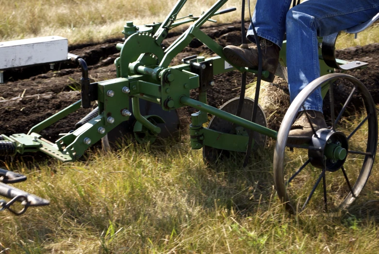 a man driving a green farm tractor in the middle of a field