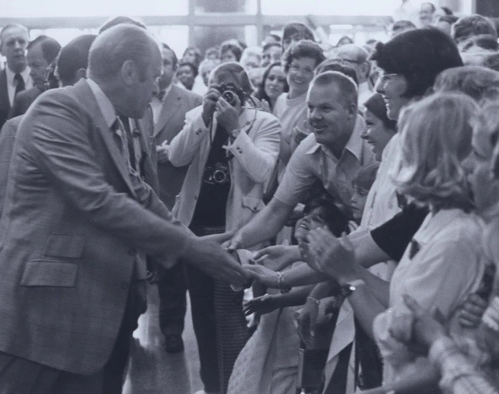 black and white po of two men shaking hands with a crowd of people