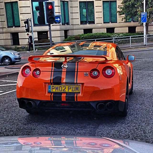 an orange sports car driving down the road