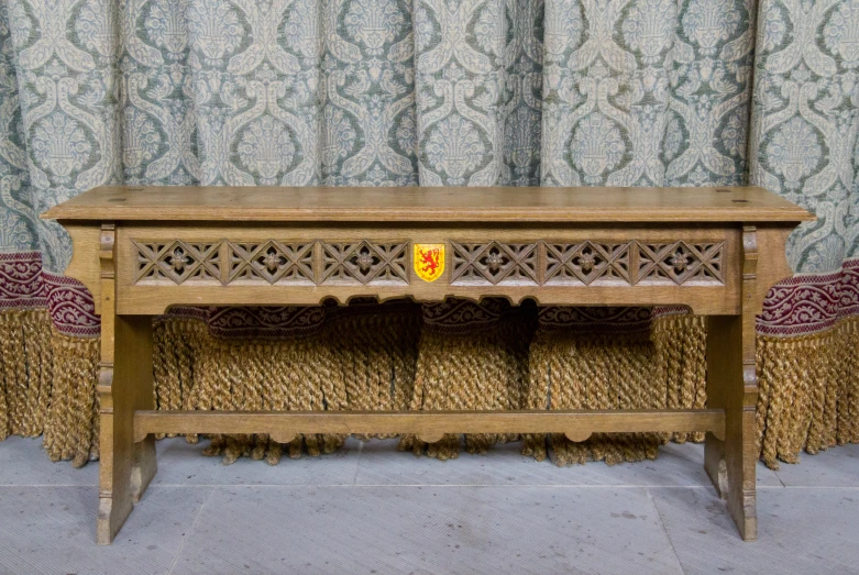 an old wooden table is shown in front of curtains