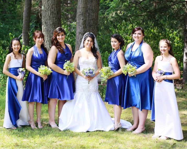 a group of bridesmaids posing for a po in front of some trees