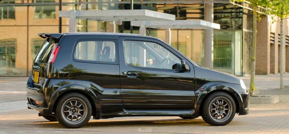 small hatchback minivan with rear luggage compartment parked on bricked side walk way